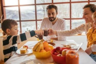 Foto de una familia joven conformada por padre, madre, niño y niña, desayunando